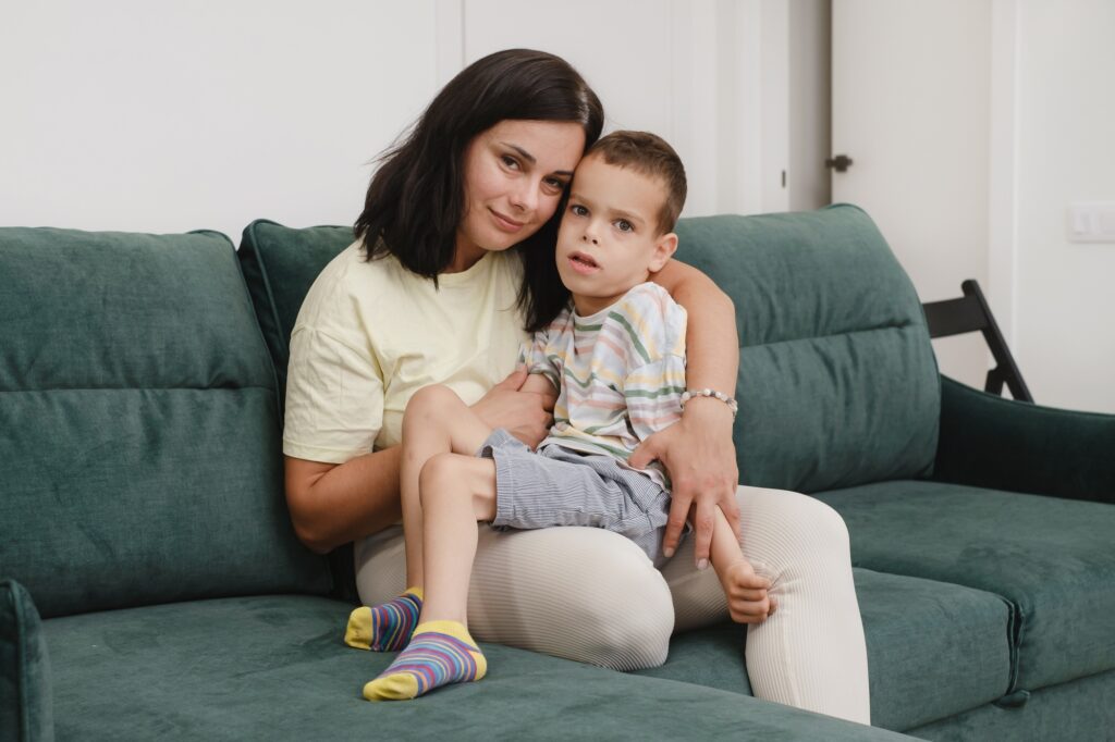 .Mother with disabled child with cerebral palsy on sofa having fun